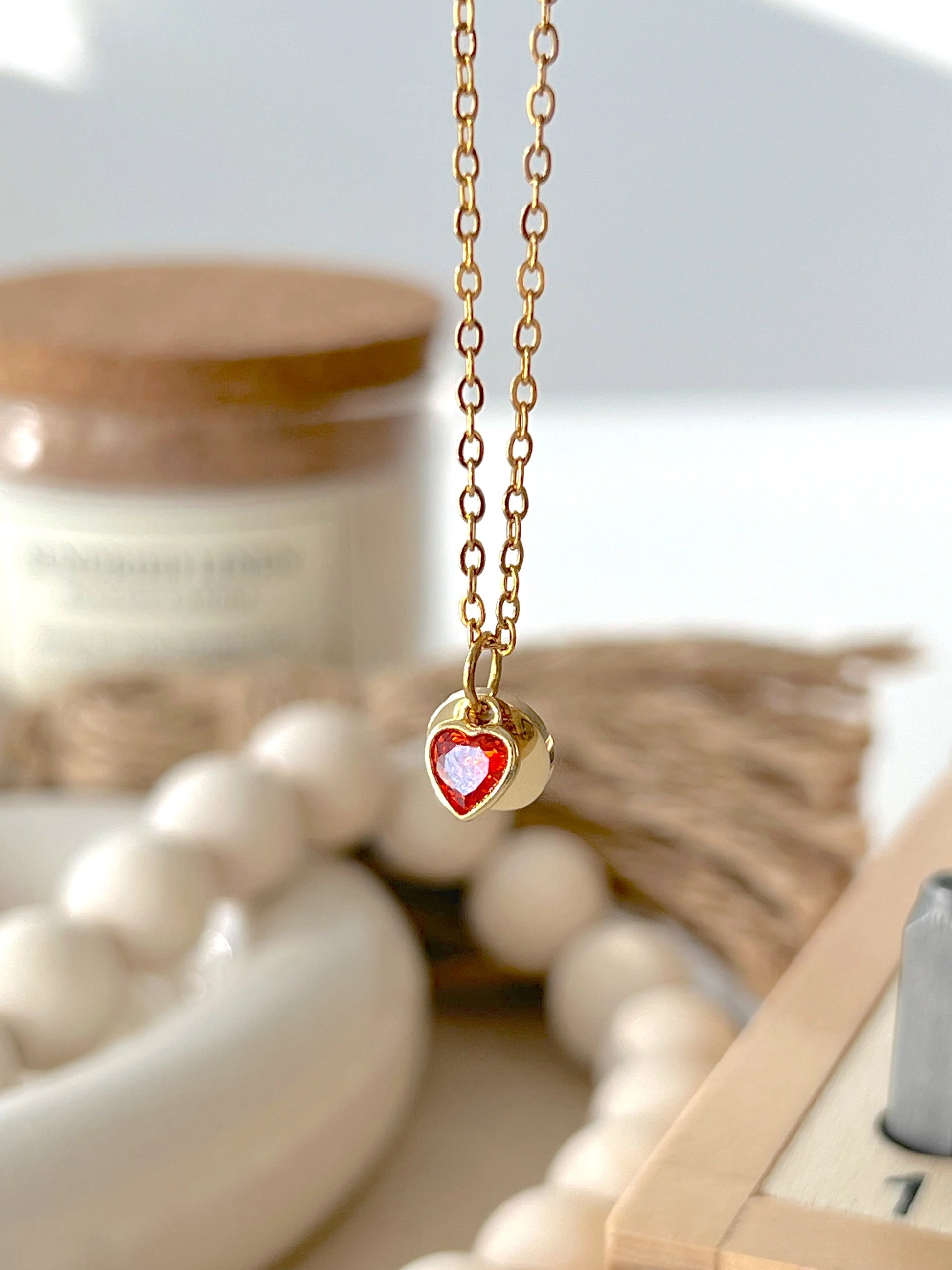 Gold necklace with a red heart pendant on a blurred background