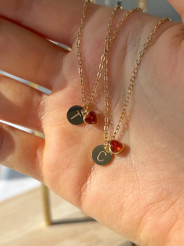 Two gold necklaces with round pendants on a hand
