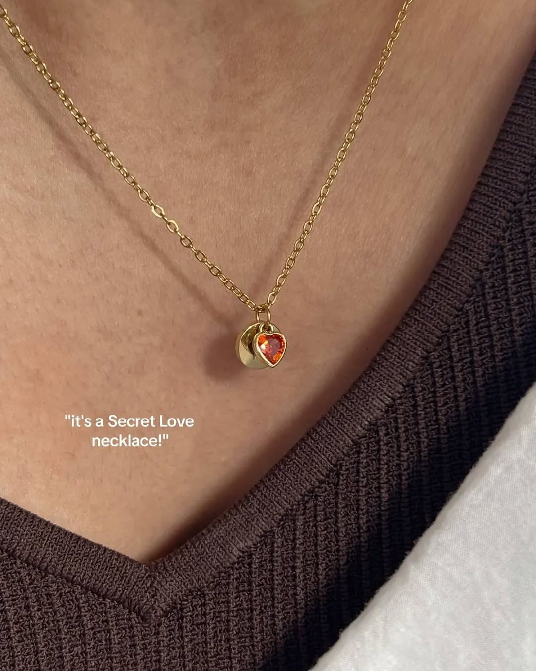 Gold necklace with a heart-shaped pendant worn by a person, on a plain background.